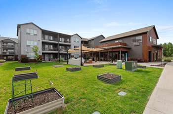 Apartment complex with green lawn and benches.